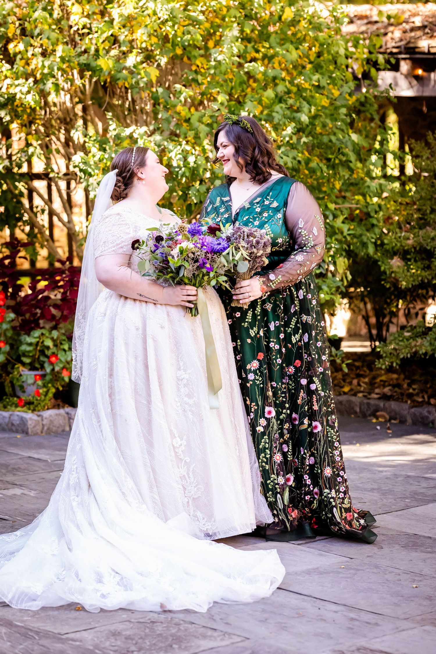Two people in wedding attire share a joyful moment together while holding beautiful wildflower bouquets.