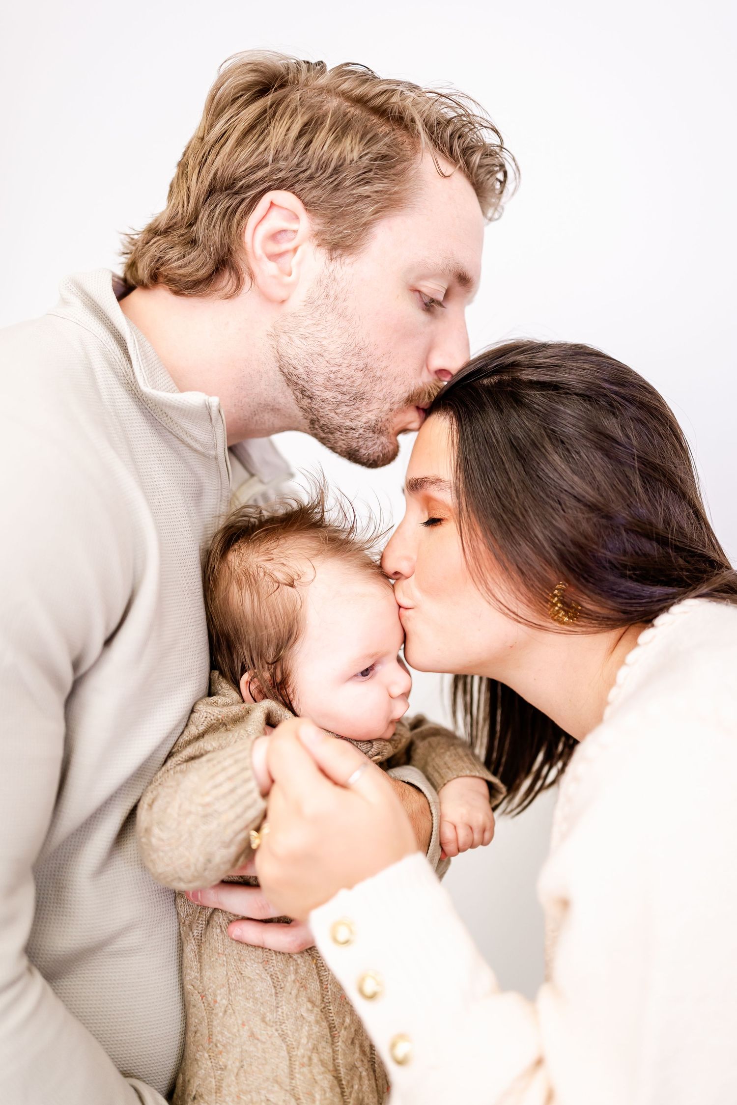 Intimate family portrait showing tender kisses and embraces against a white background.