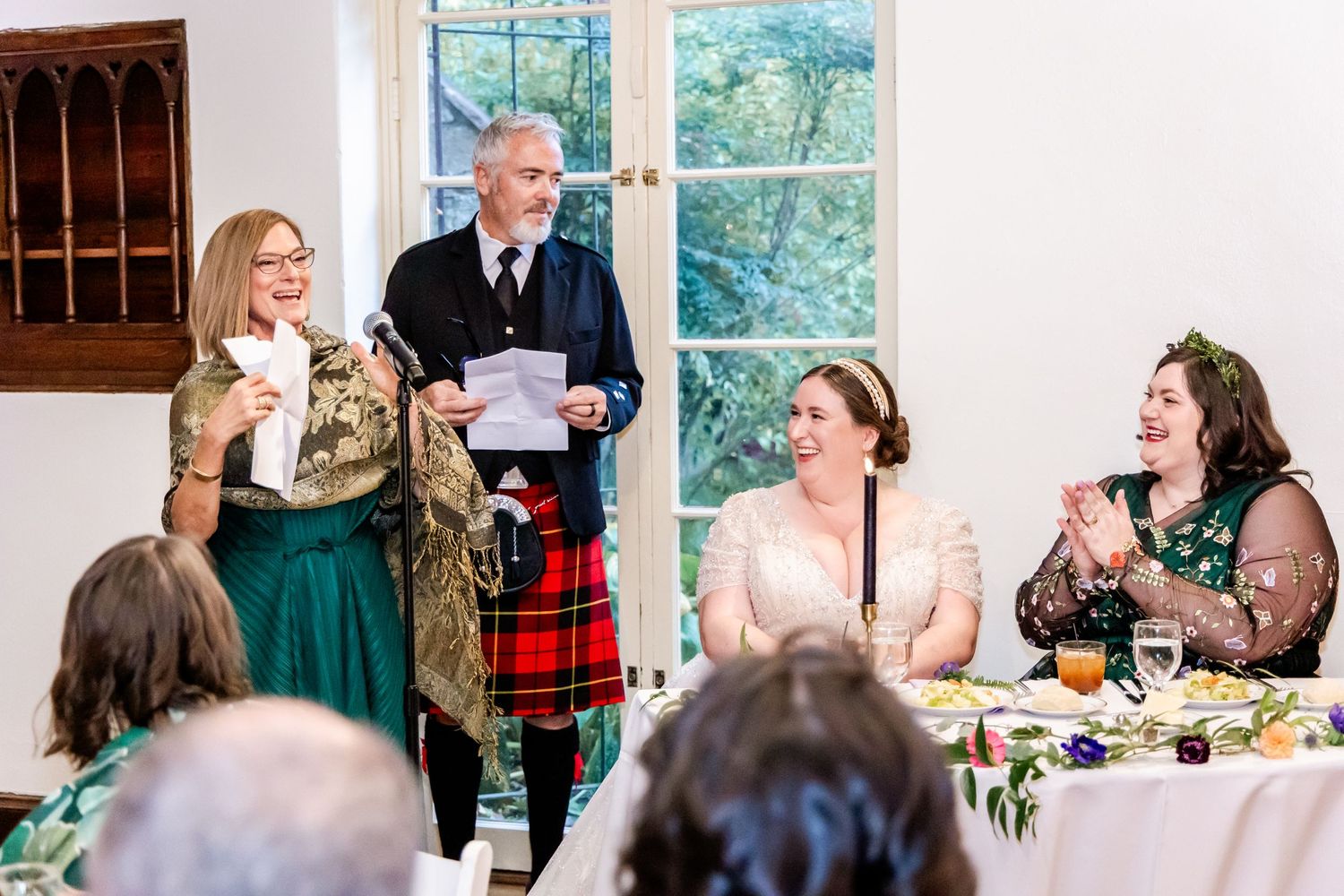 Wedding reception toast with guests seated at decorated tables indoors.