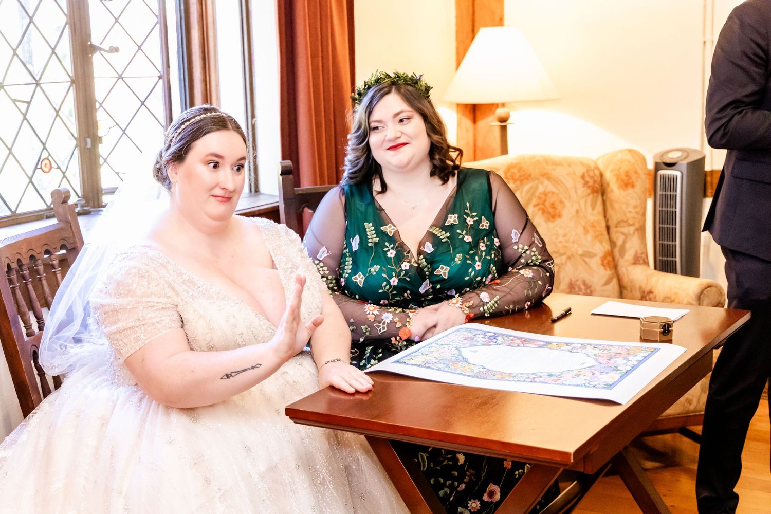 People gathered around a wooden table during a wedding ceremony document signing.