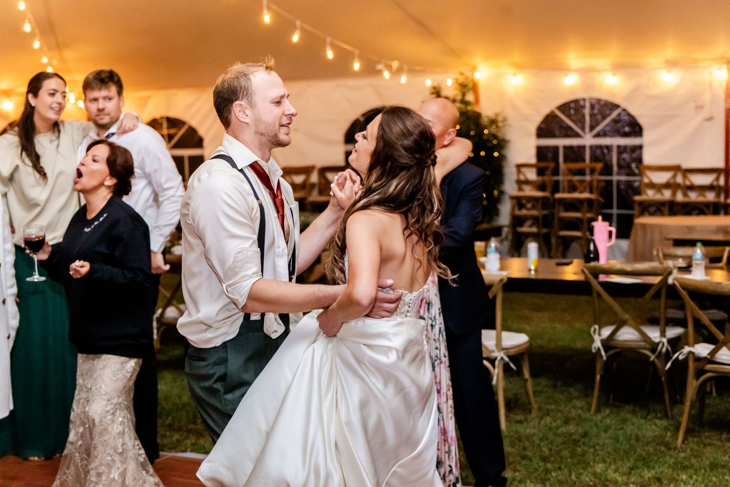 Couples dancing and celebrating at an outdoor wedding reception under string lights.