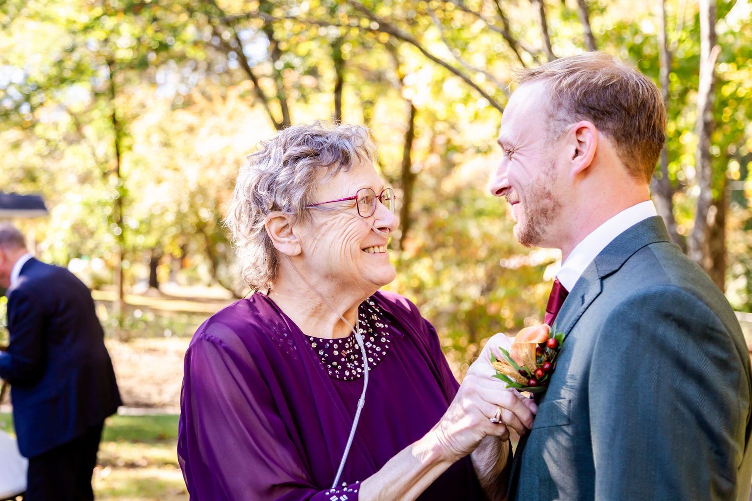 Wedding guests in purple attire mingle during an outdoor celebration.