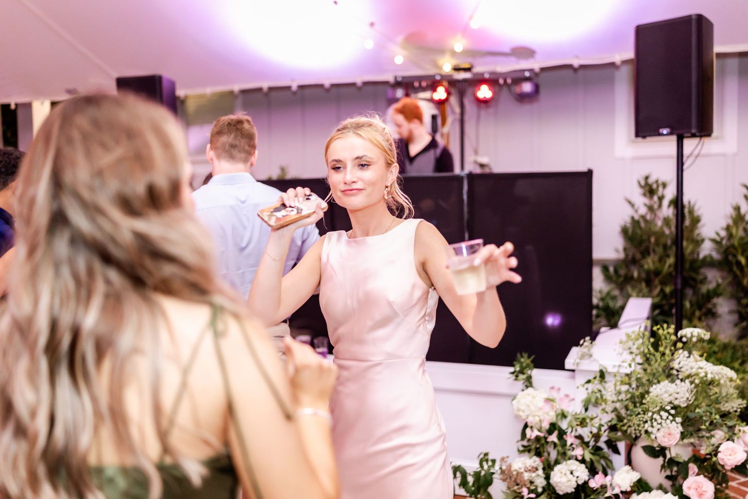 Wedding reception dance floor filled with guests celebrating and dancing under warm lighting.