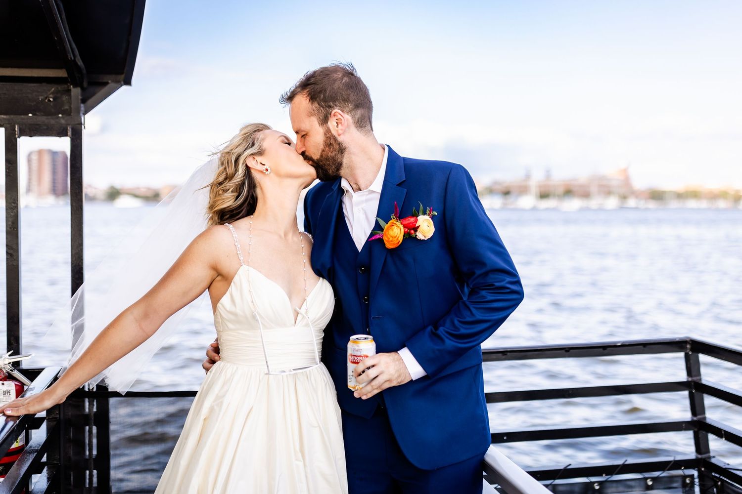 A romantic waterfront wedding portrait featuring a bright blue suit and flowing white dress.