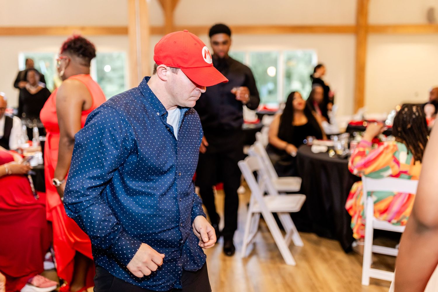 People dancing and celebrating at an indoor event with wooden walls and natural lighting.