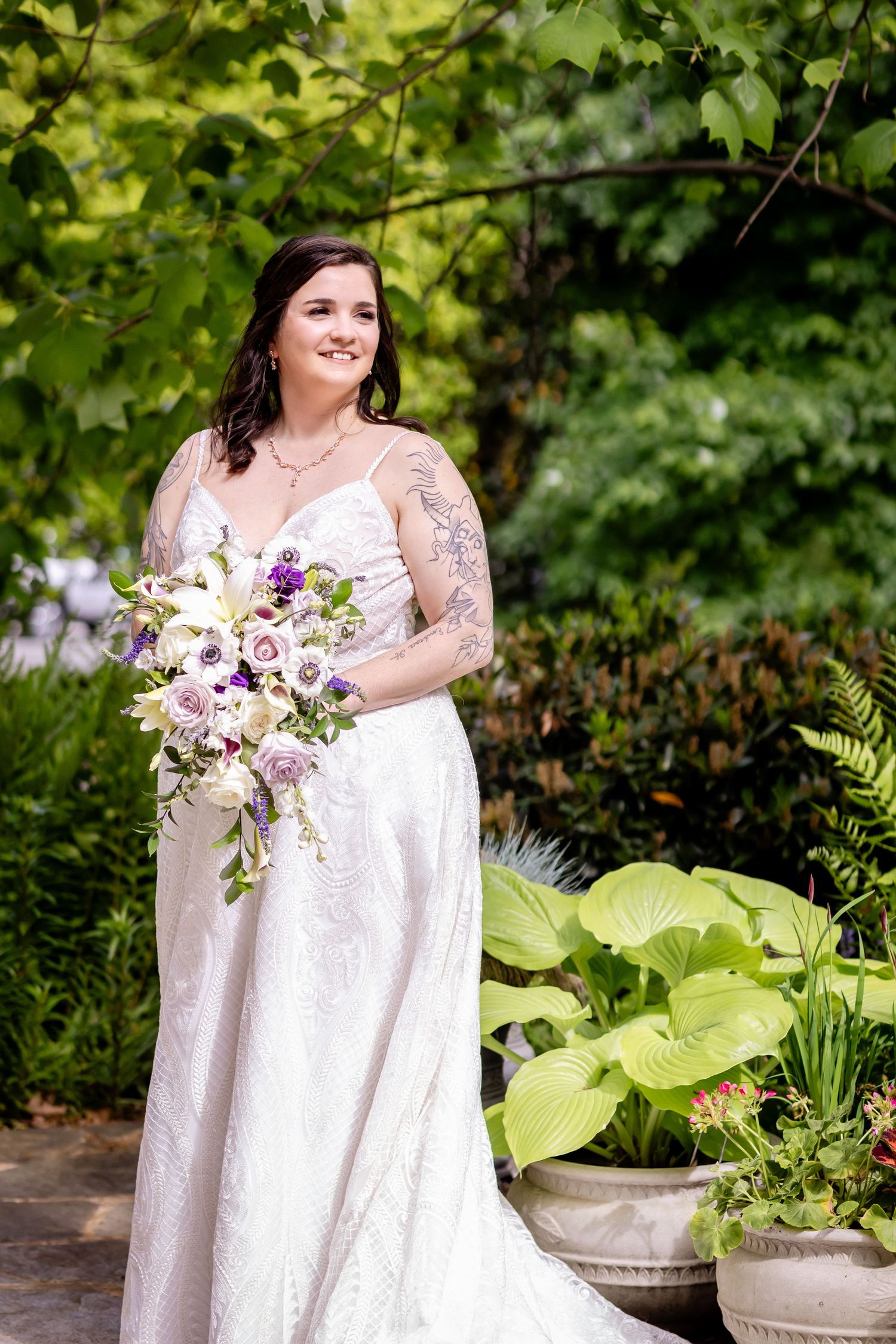 Wedding portrait with beautiful floral bouquet in garden setting with lush greenery.