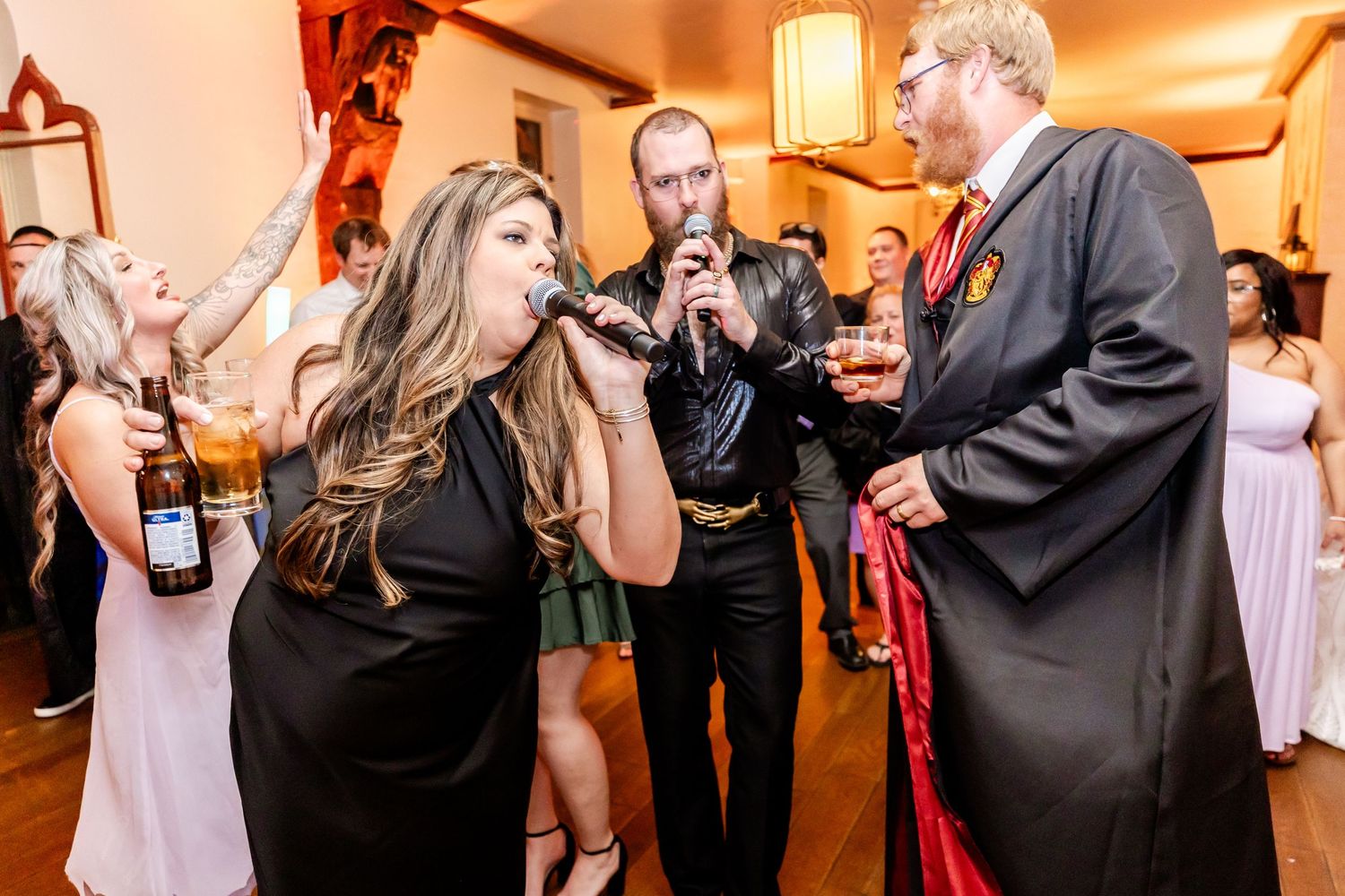 Party guests singing and holding drinks during a lively indoor celebration.