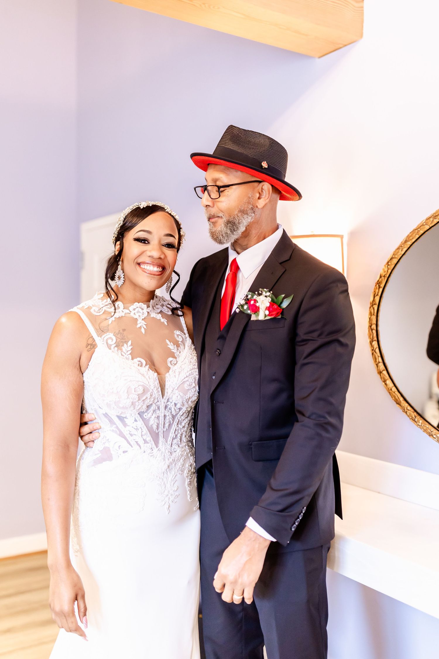 Formal wedding portrait in an elegant indoor setting with white and red accents.