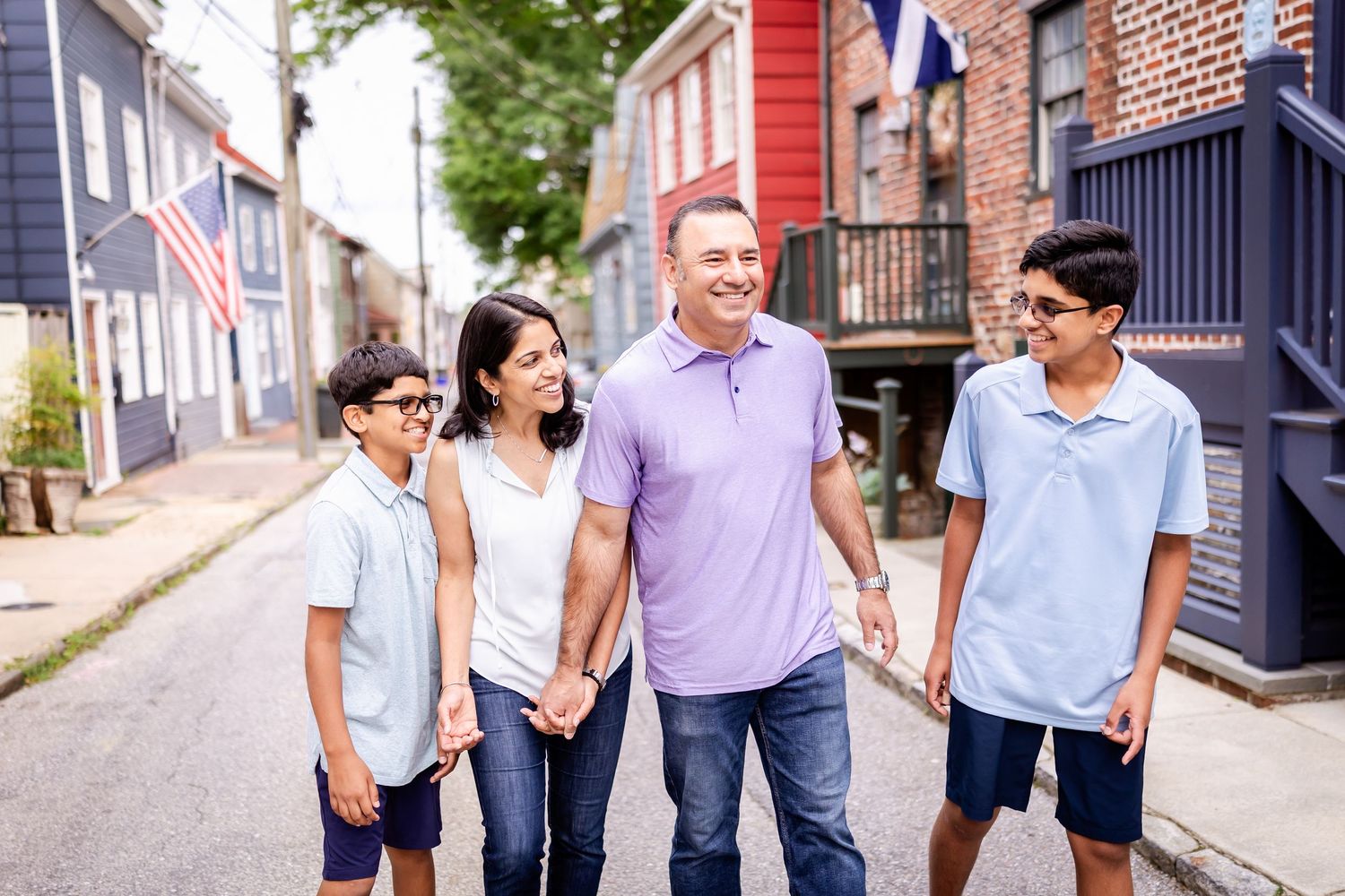 A family walks together and smiles while exploring a charming historic neighborhood with brick buildings.