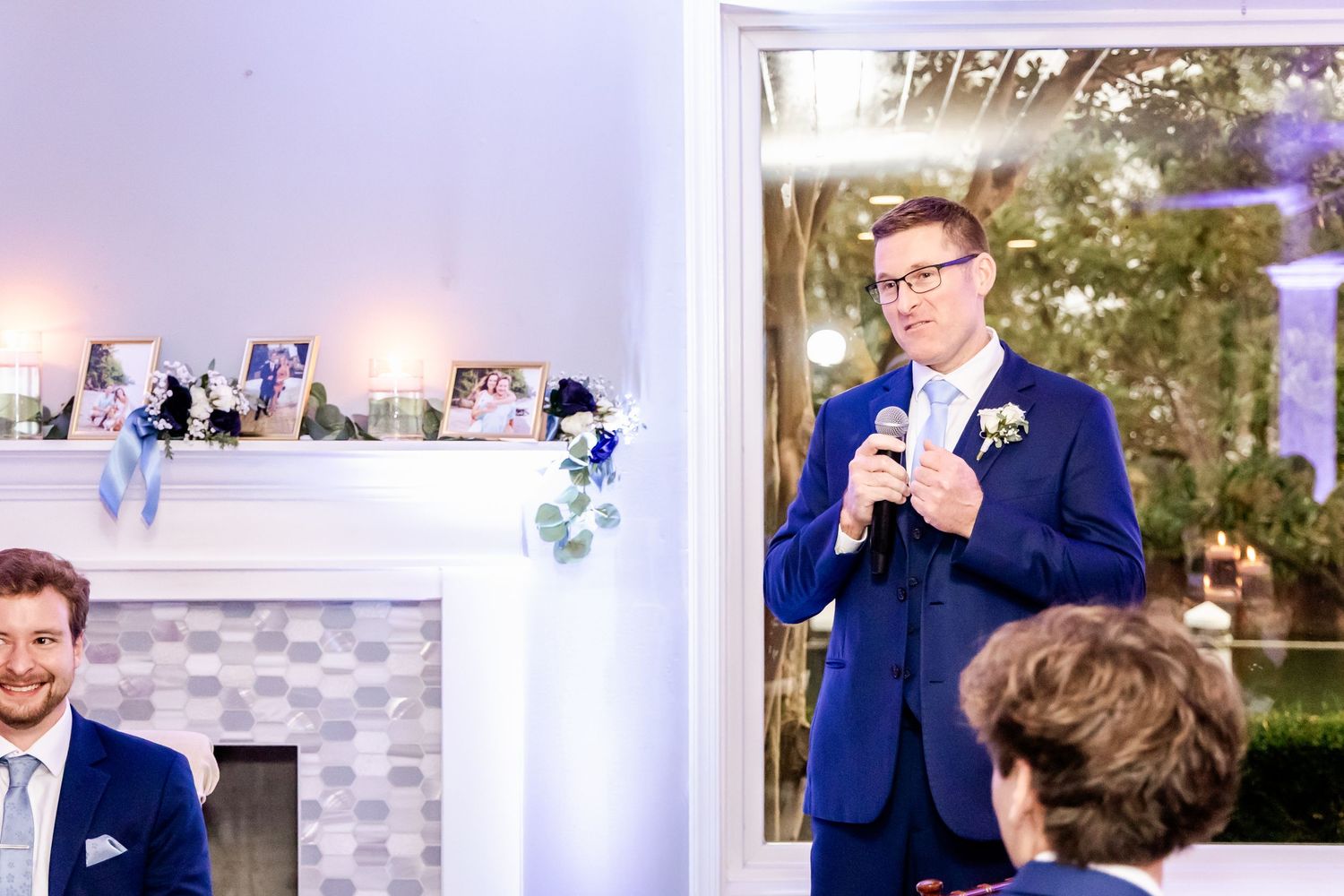 A wedding reception scene with guests and speakers in formal attire.