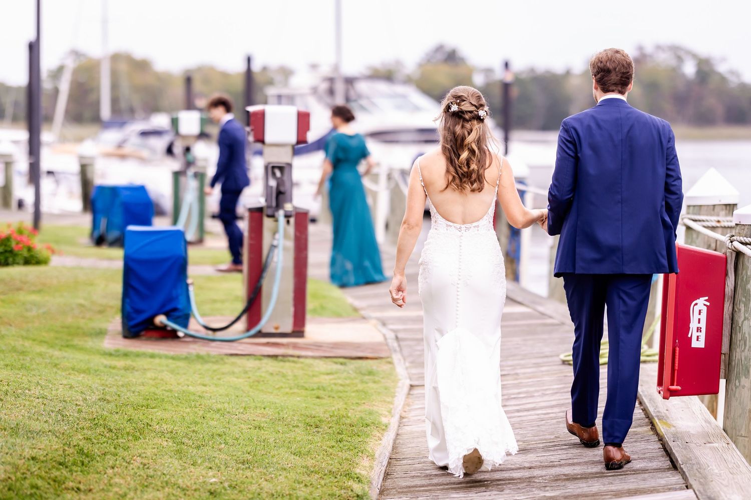 Wedding party walks along a waterfront path with scenic views in the background.