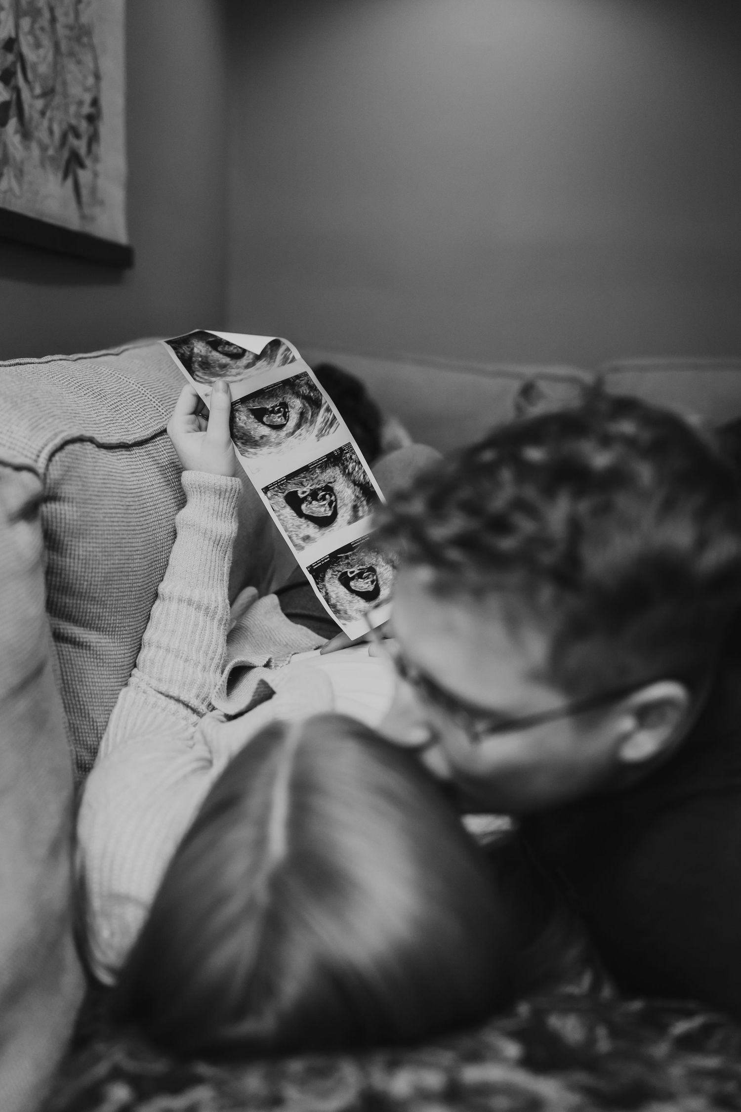 Black and white photo showing ultrasound images being held while looking at baby scans.