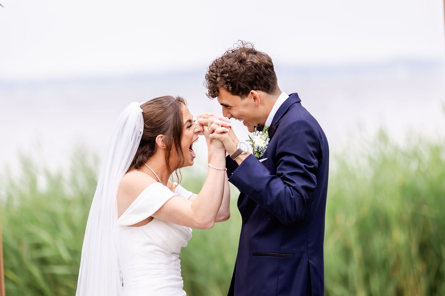 Wedding couple sharing a romantic moment outdoors with tall grass in the background.