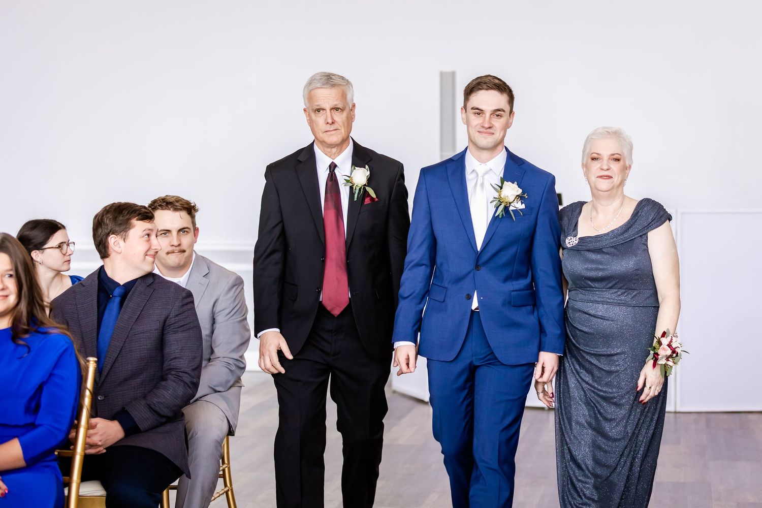 Wedding party members in formal attire gathered in a bright indoor space.