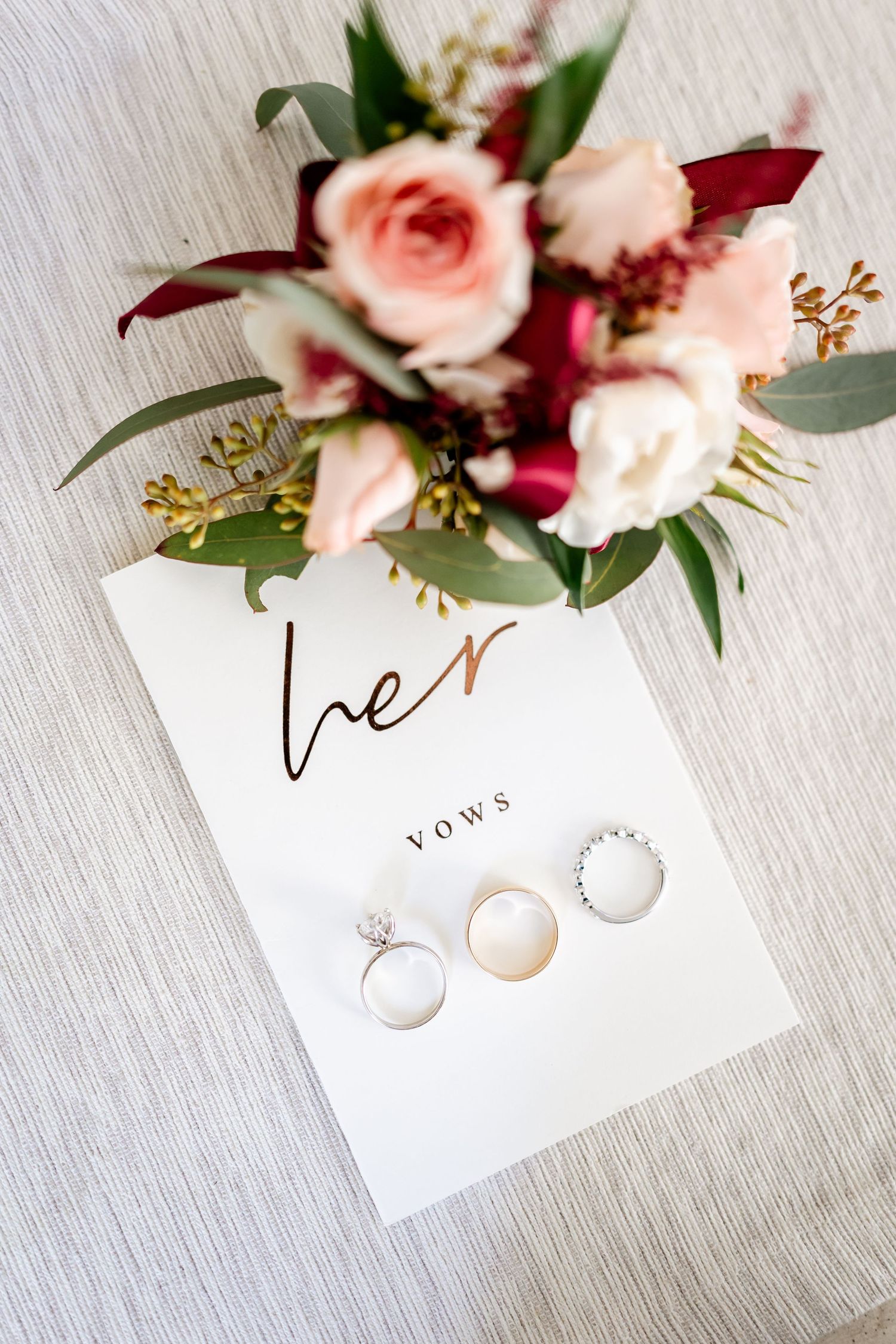 Wedding invitation cards decorated with delicate pink roses and greenery on a light textured surface.