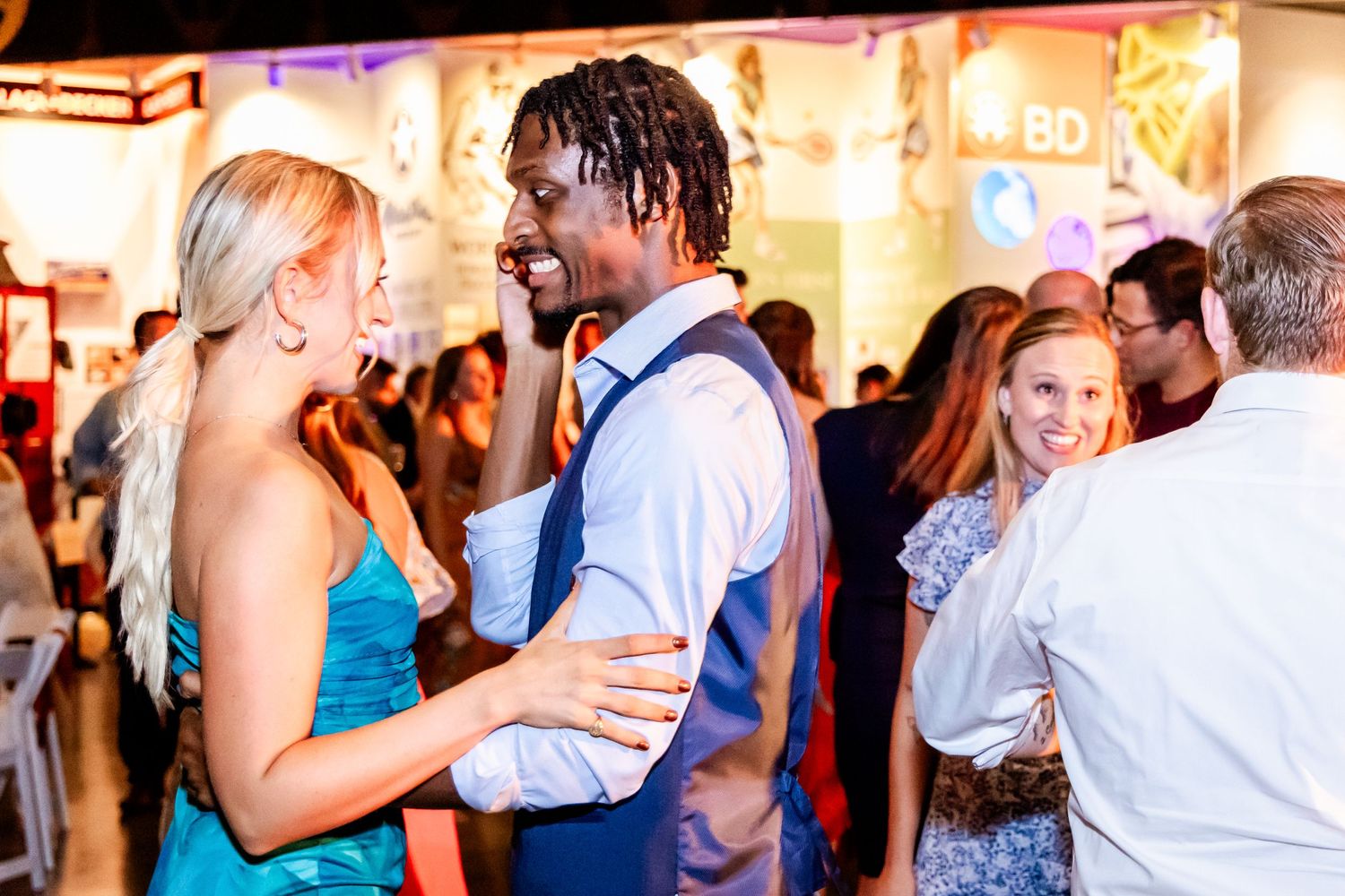 People dancing and socializing at a lively indoor event with bright lighting.