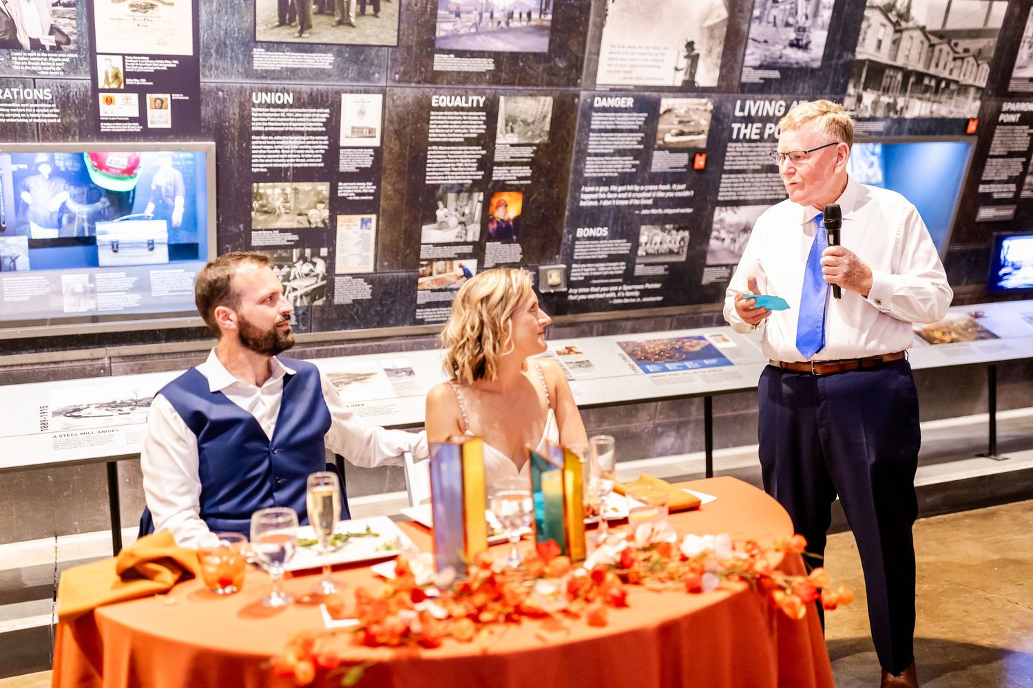 Reception scene in museum gallery with orange tablecloth and historical displays.
