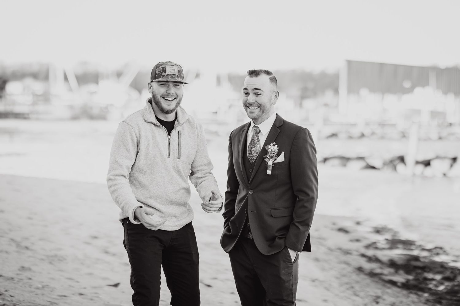 Two people share a candid black and white moment on a beach.