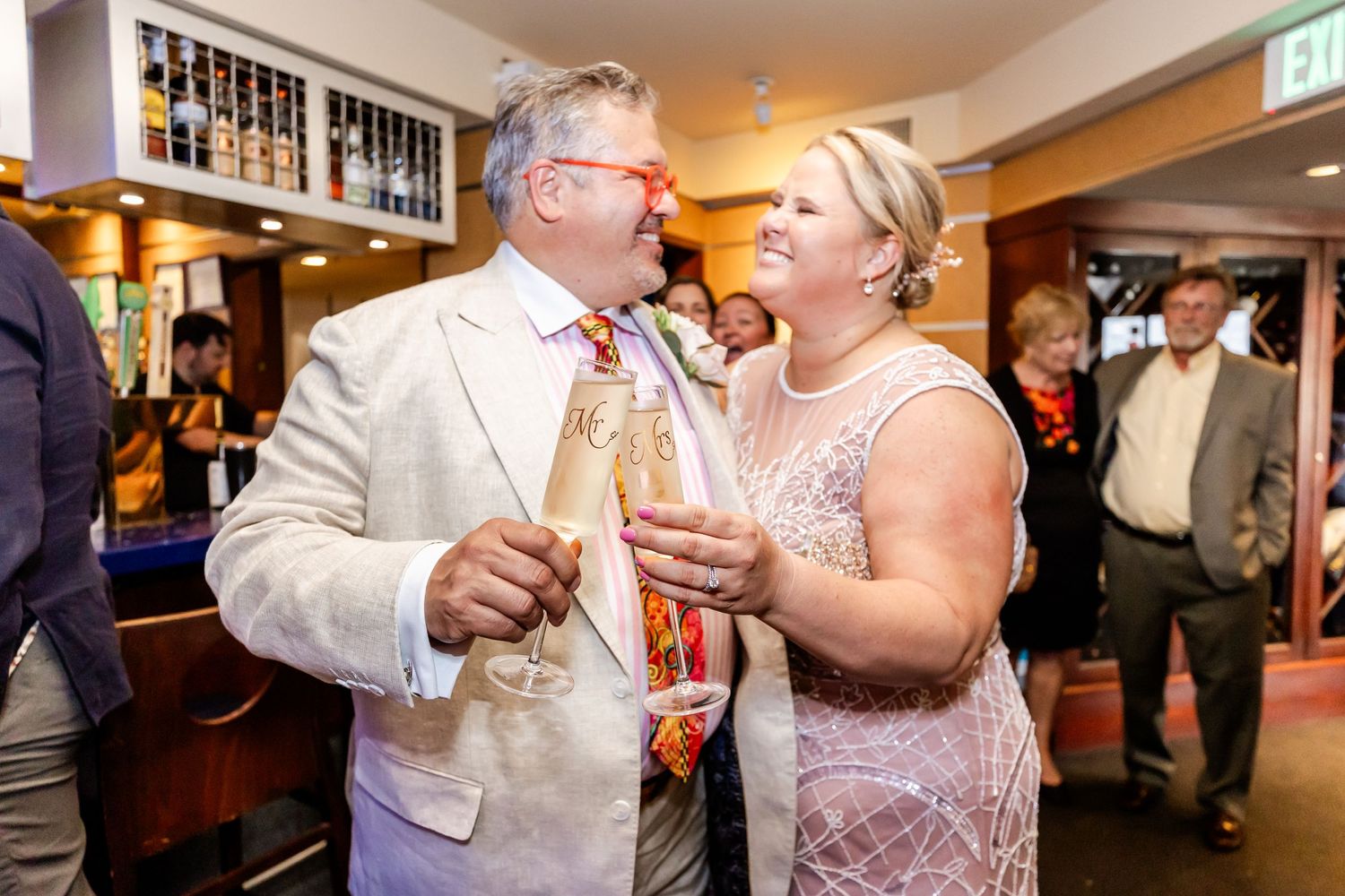 Well-dressed couple sharing drinks and conversation at indoor social gathering.