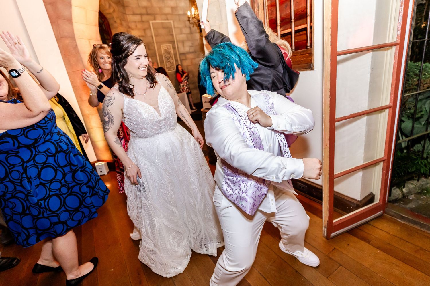 Dancers in formal attire enjoying themselves on a hardwood floor at an indoor celebration.