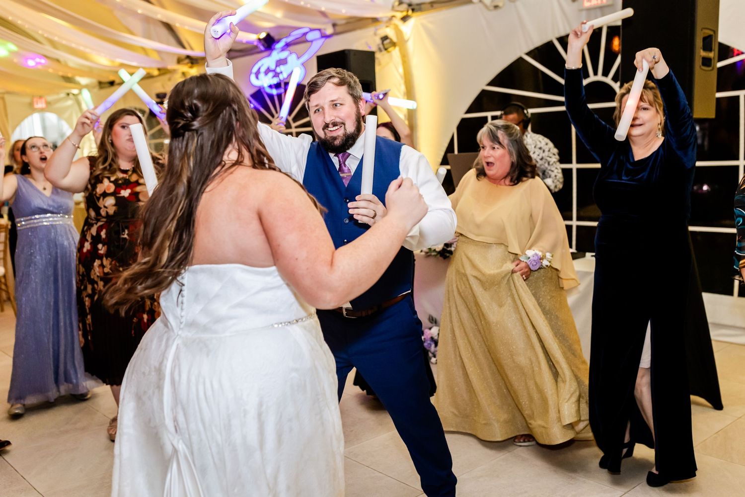 Joyful dancing and celebration at a wedding reception under an elegantly decorated tent.