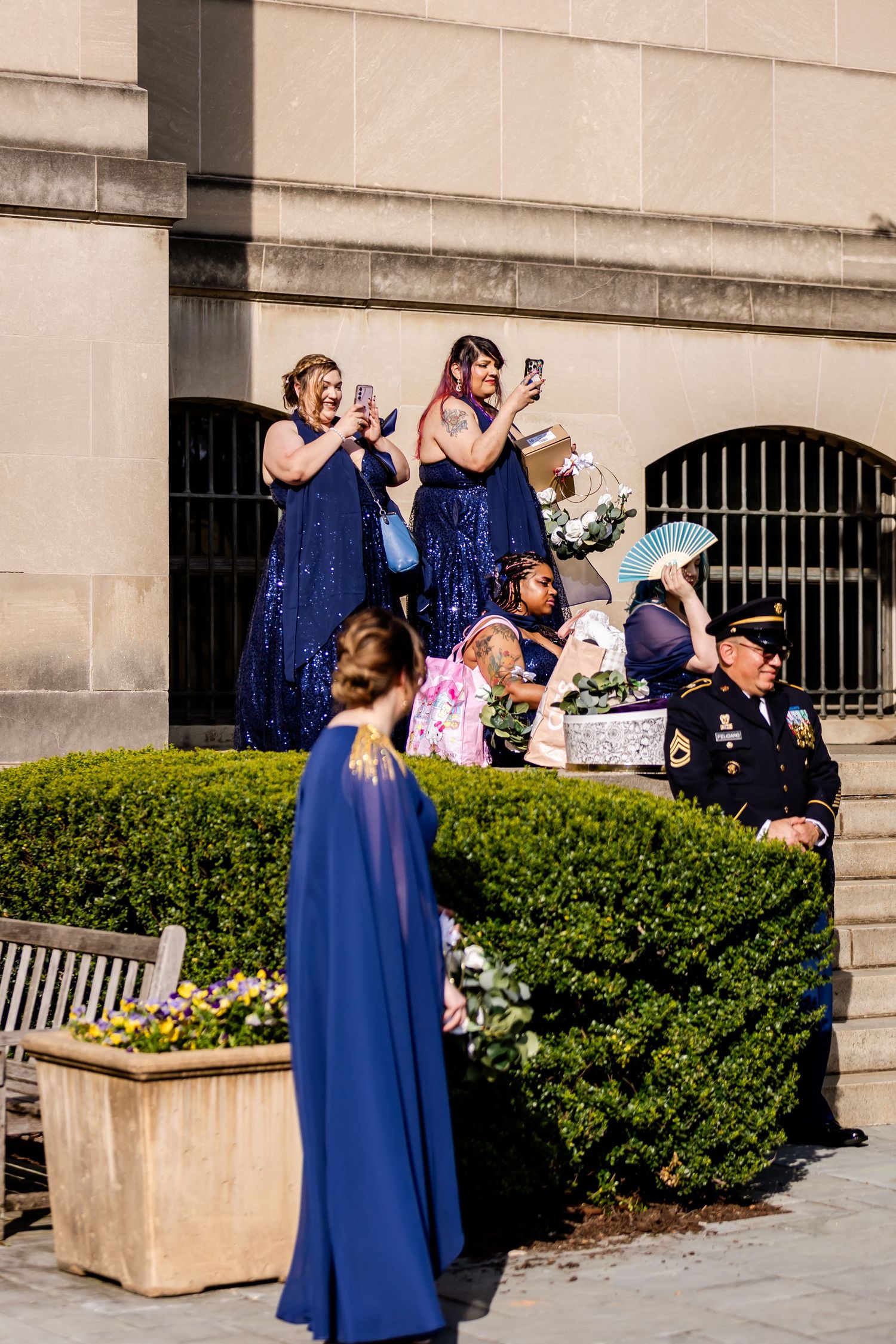 Wedding attendants in navy blue dresses take photos during outdoor celebration.