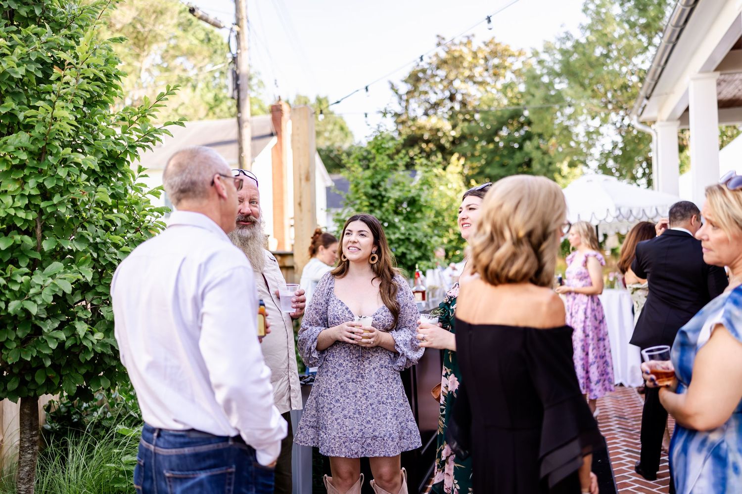 Guests mingling and socializing at an outdoor garden party on a sunny afternoon.