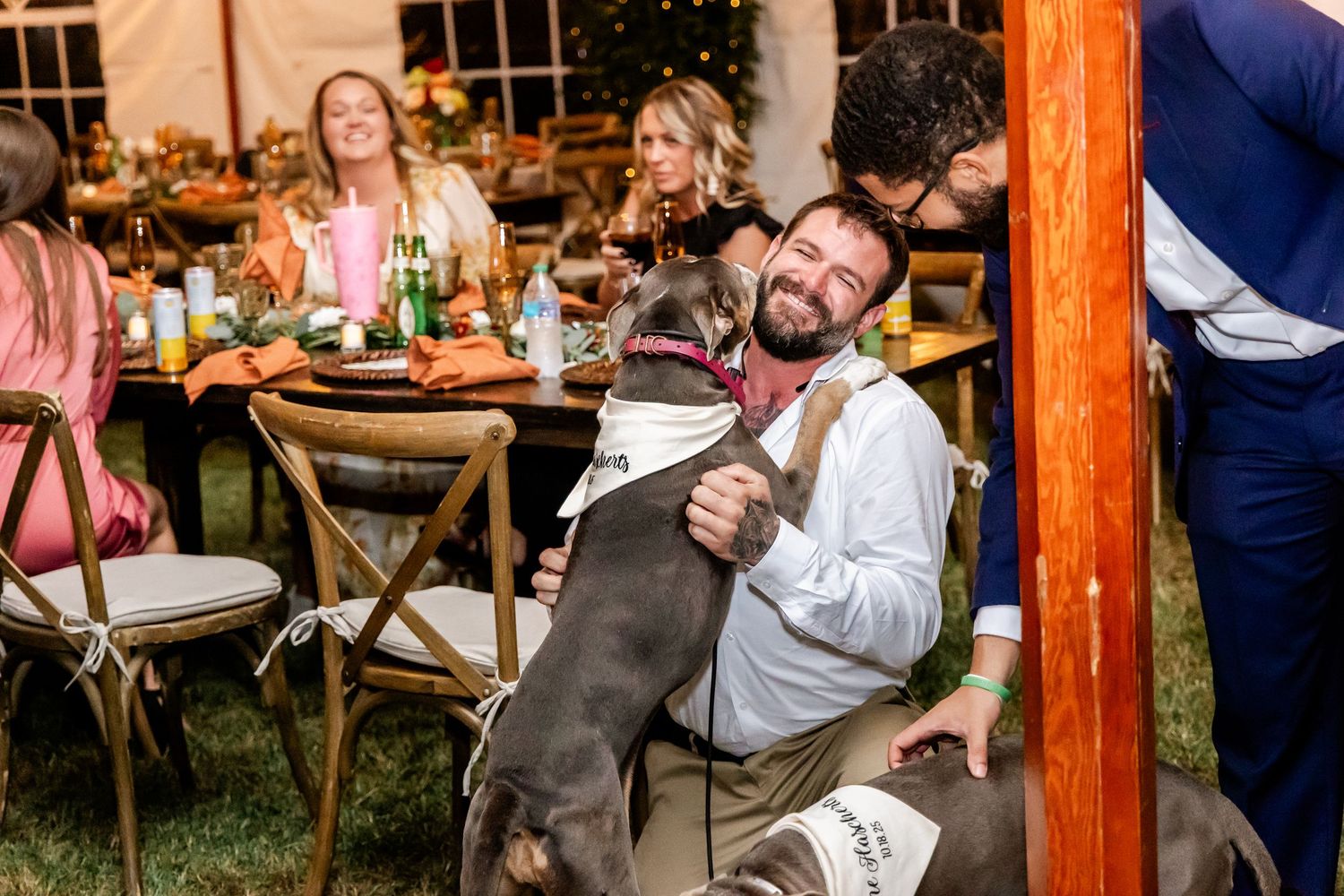 A guest relaxes at a reception table while petting a friendly dog.