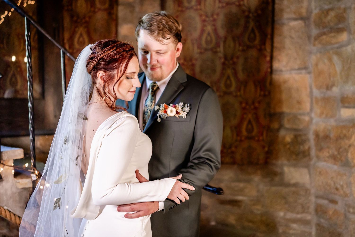 A bride and groom share an intimate moment in a rustic stone venue with romantic lighting.