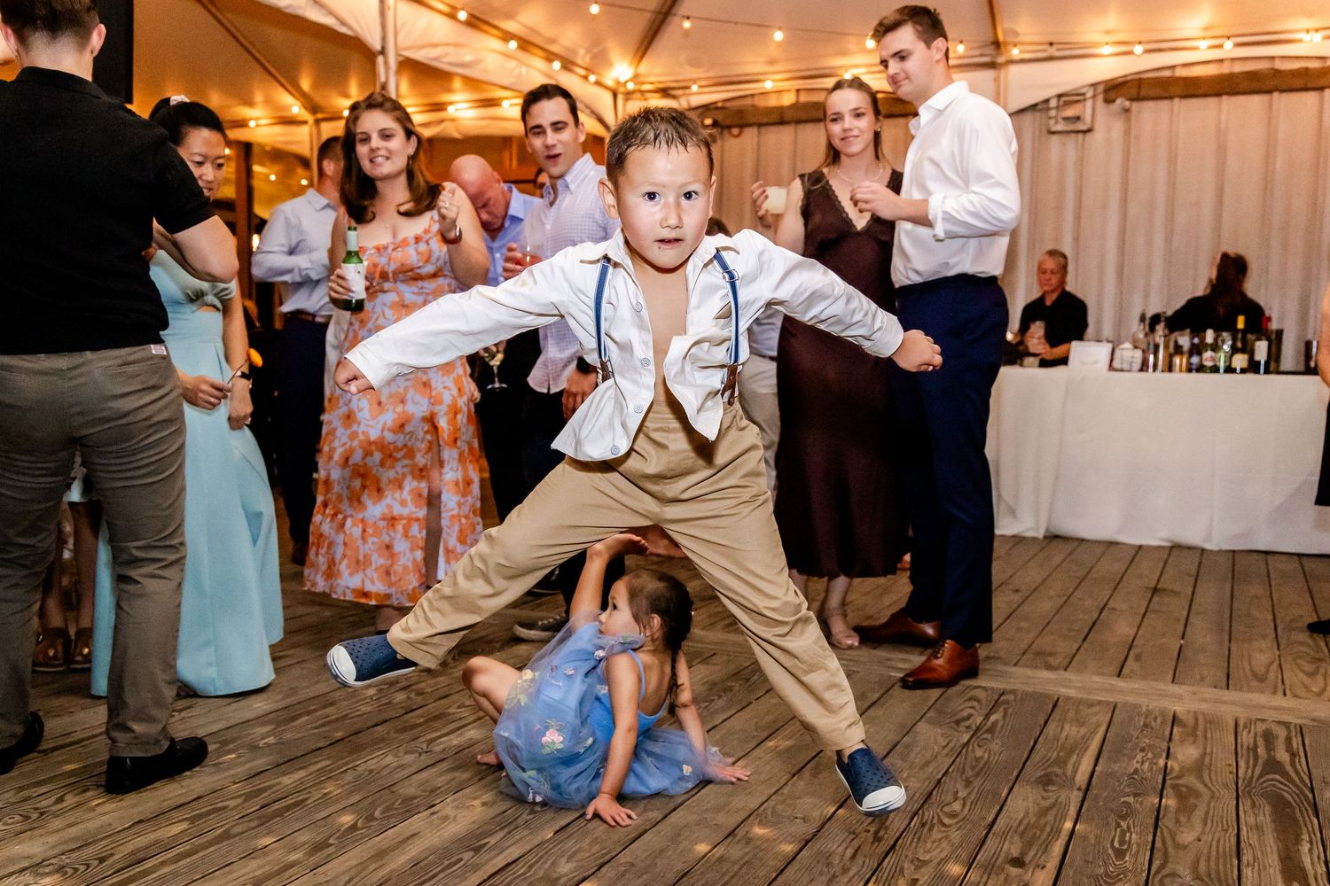 Guests dancing and celebrating on a wooden dance floor at a lively wedding reception.