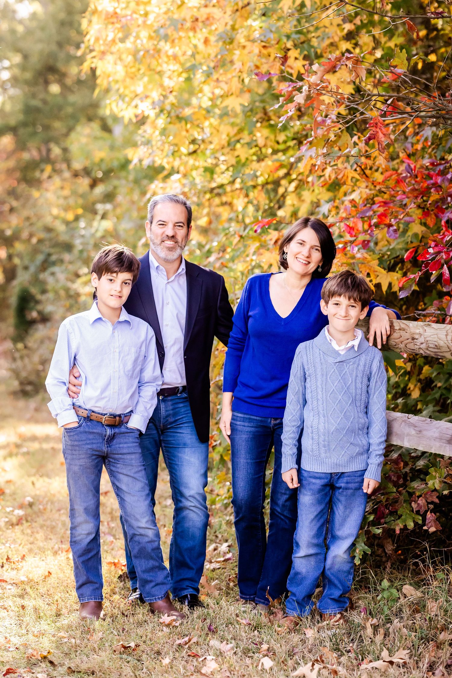 Family portrait series in autumn setting with colorful fall foliage in background.