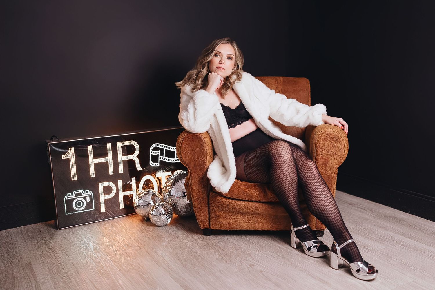 Person in black stockings and white top lounges on brown leather sofa with vintage clock decor in background.