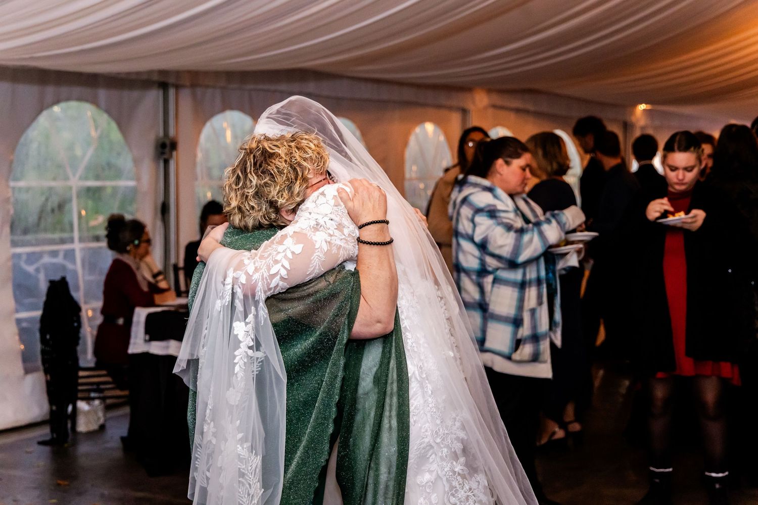 Wedding guests mingle and socialize during a tented reception celebration.