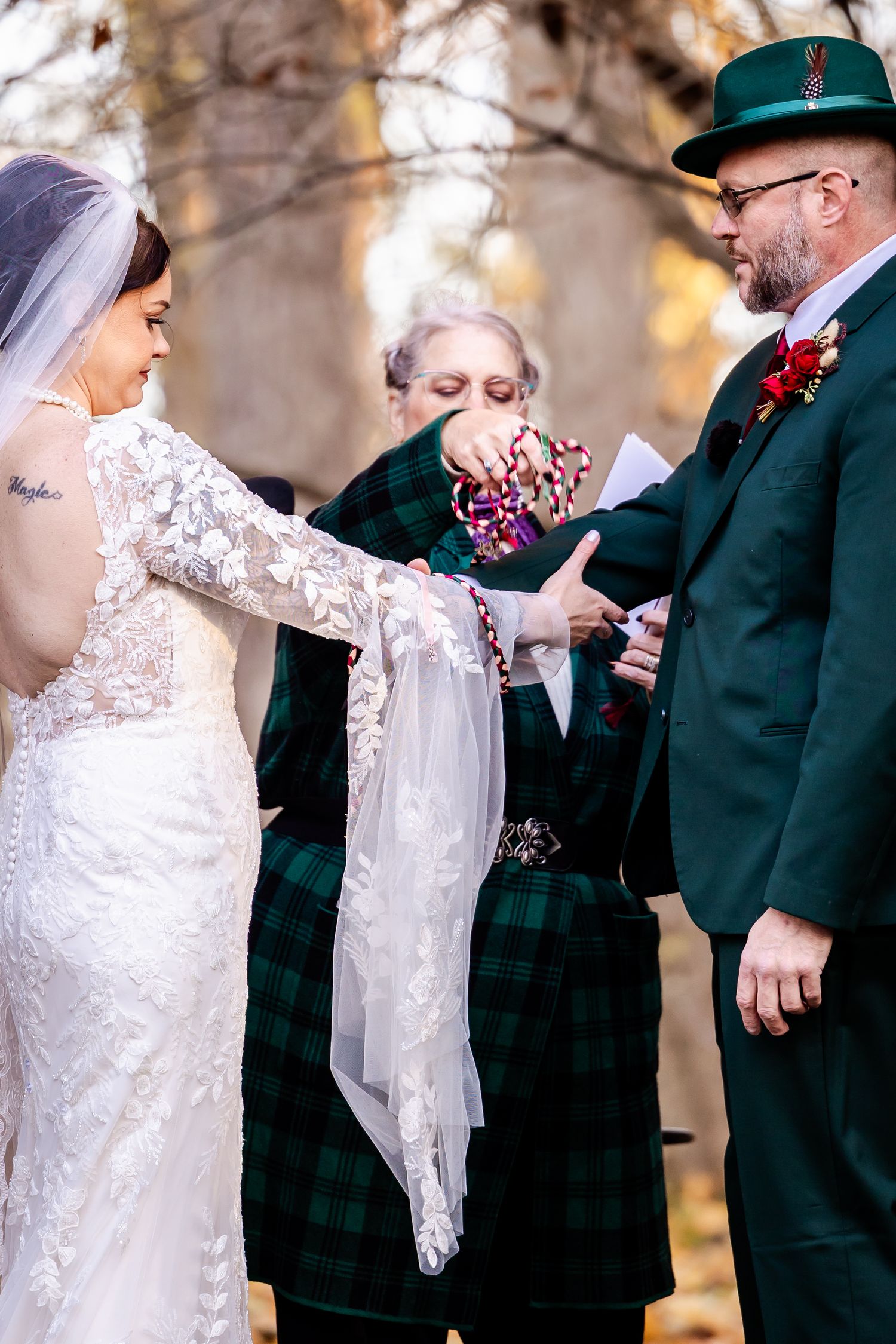 Wedding ceremony details showing lace dress and formal attire against autumn background.