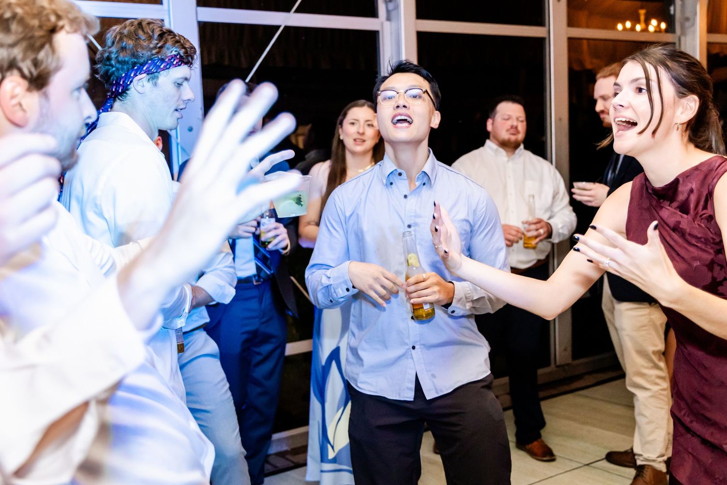 Wedding guests laughing and dancing energetically at reception party.