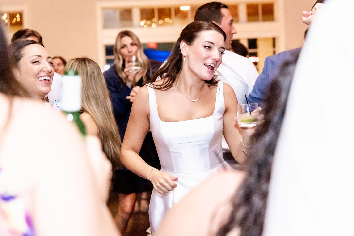 Wedding reception guests dancing and celebrating in a warmly lit indoor venue.