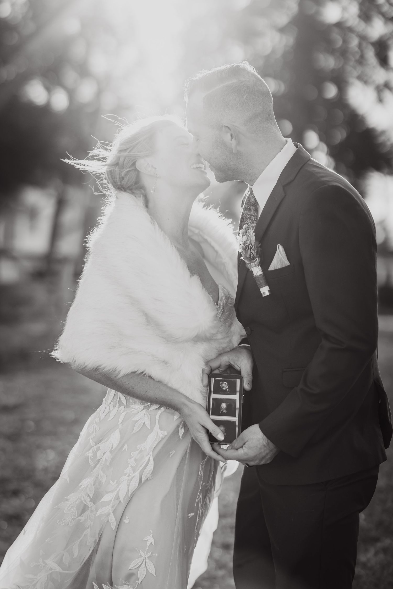 A romantic black and white wedding photo capturing an intimate moment between newlyweds in winter attire.