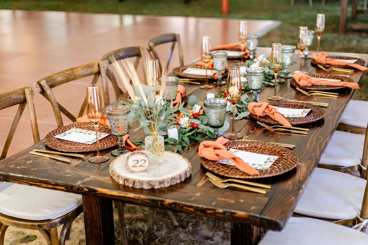 Elegant rustic wedding table settings with copper chargers and greenery decorations.