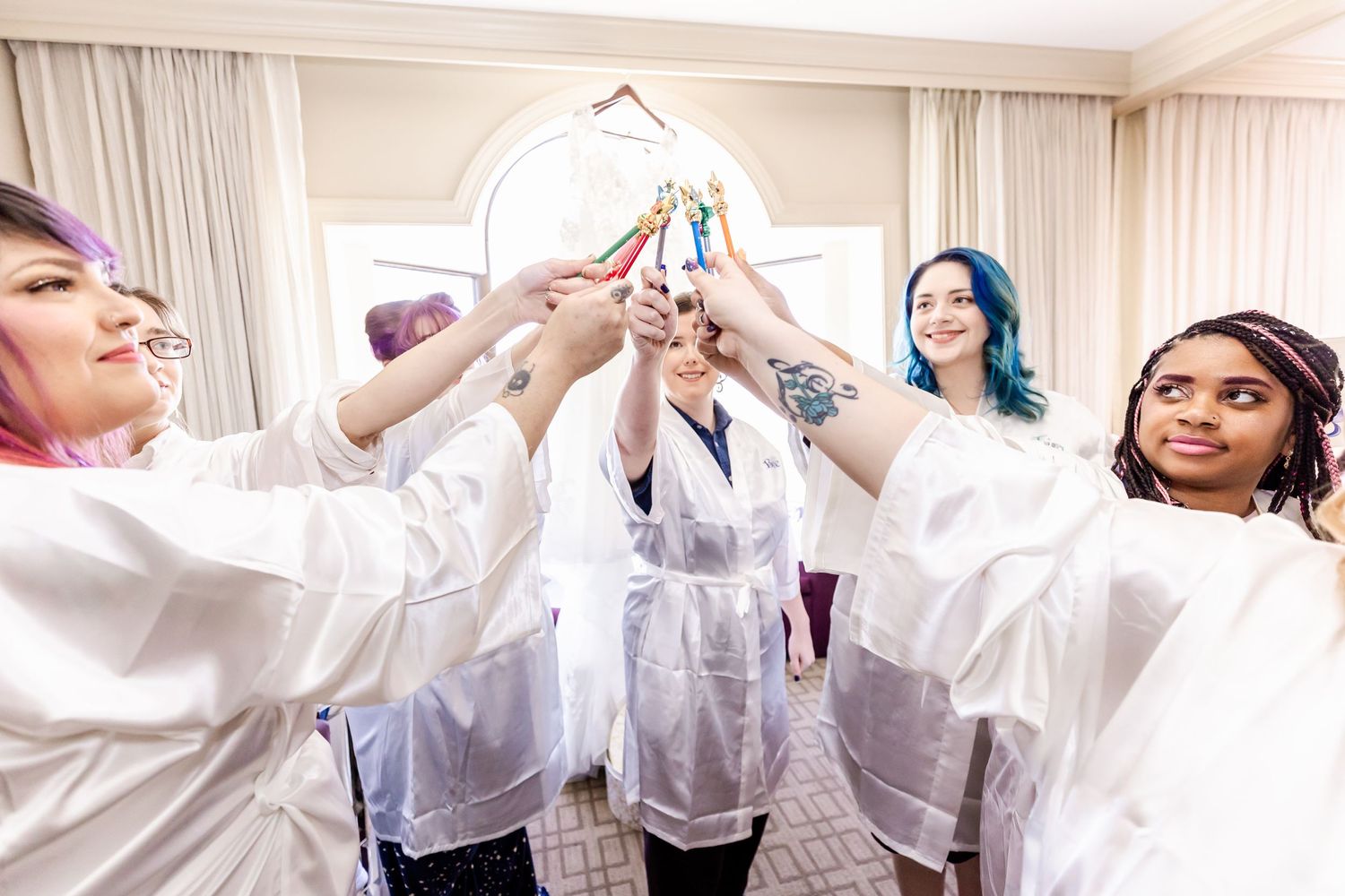 Group raising champagne glasses in white robes during pre-wedding celebration.