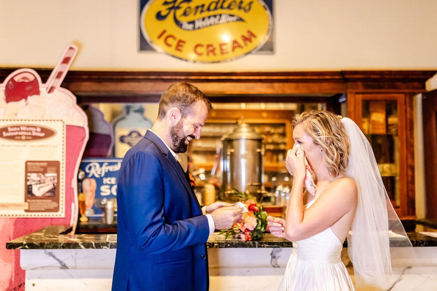 Wedding couple exchanges rings in front of vintage Kennier's Ice Cream shop sign.