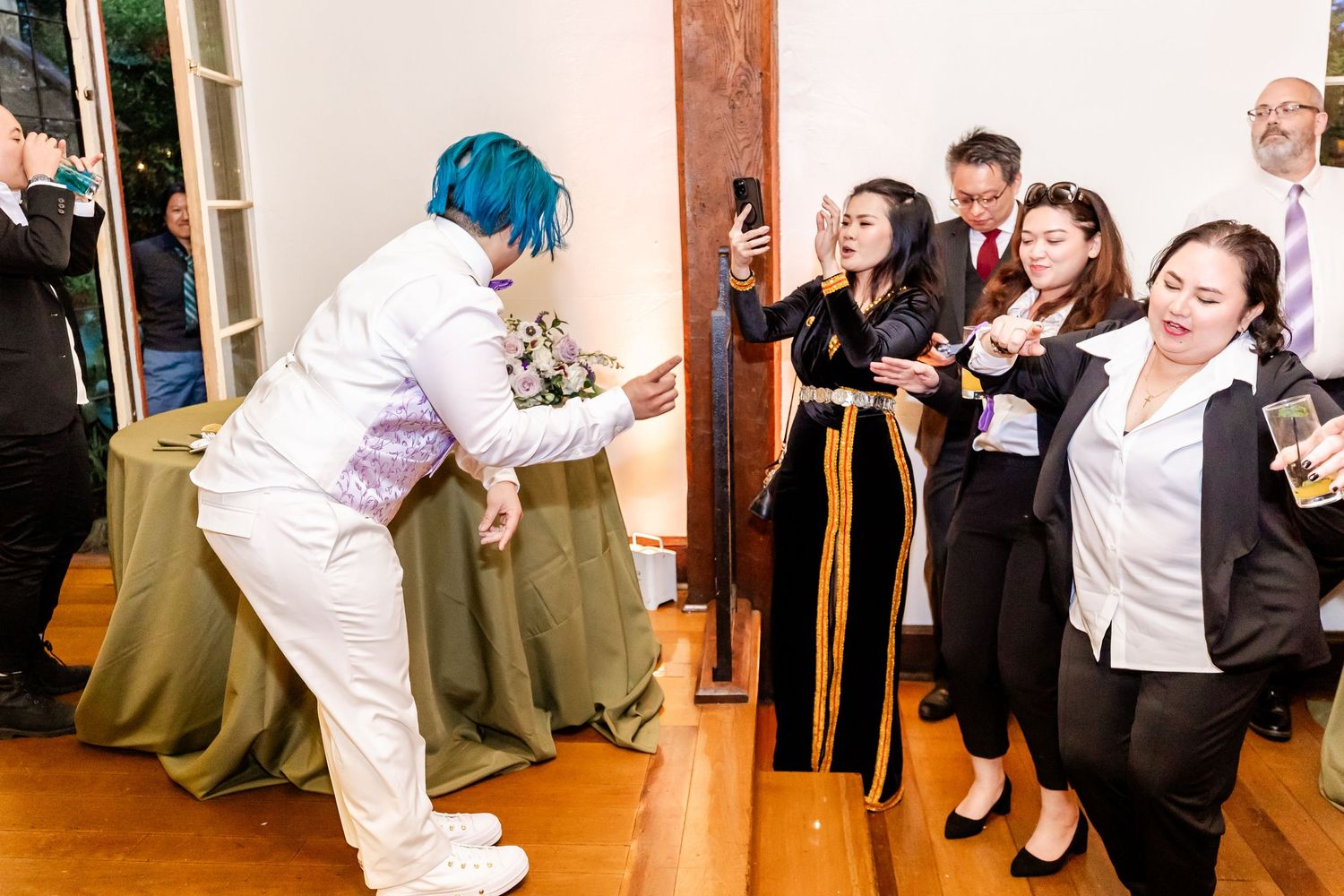 Performer in white outfit with blue hair entertains wedding guests during reception.