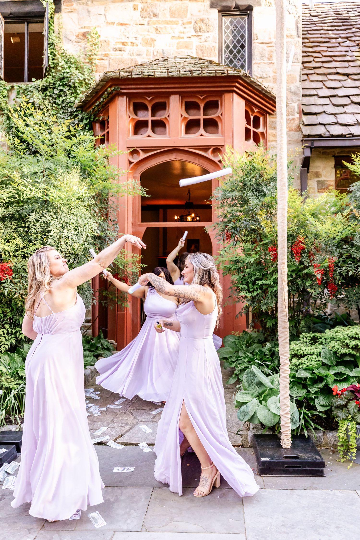Wedding guests in flowing dresses dancing together outside a gothic archway.