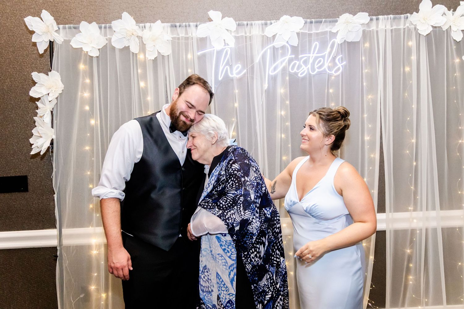 Candid moments between wedding party members in front of an elegant draped backdrop.