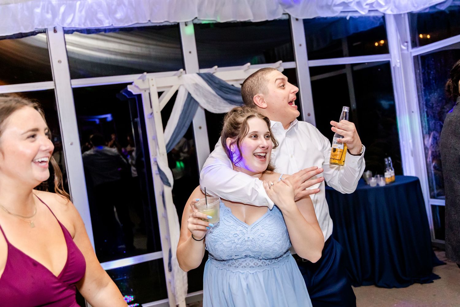 Wedding guests share enthusiastic dance moves during reception celebration.