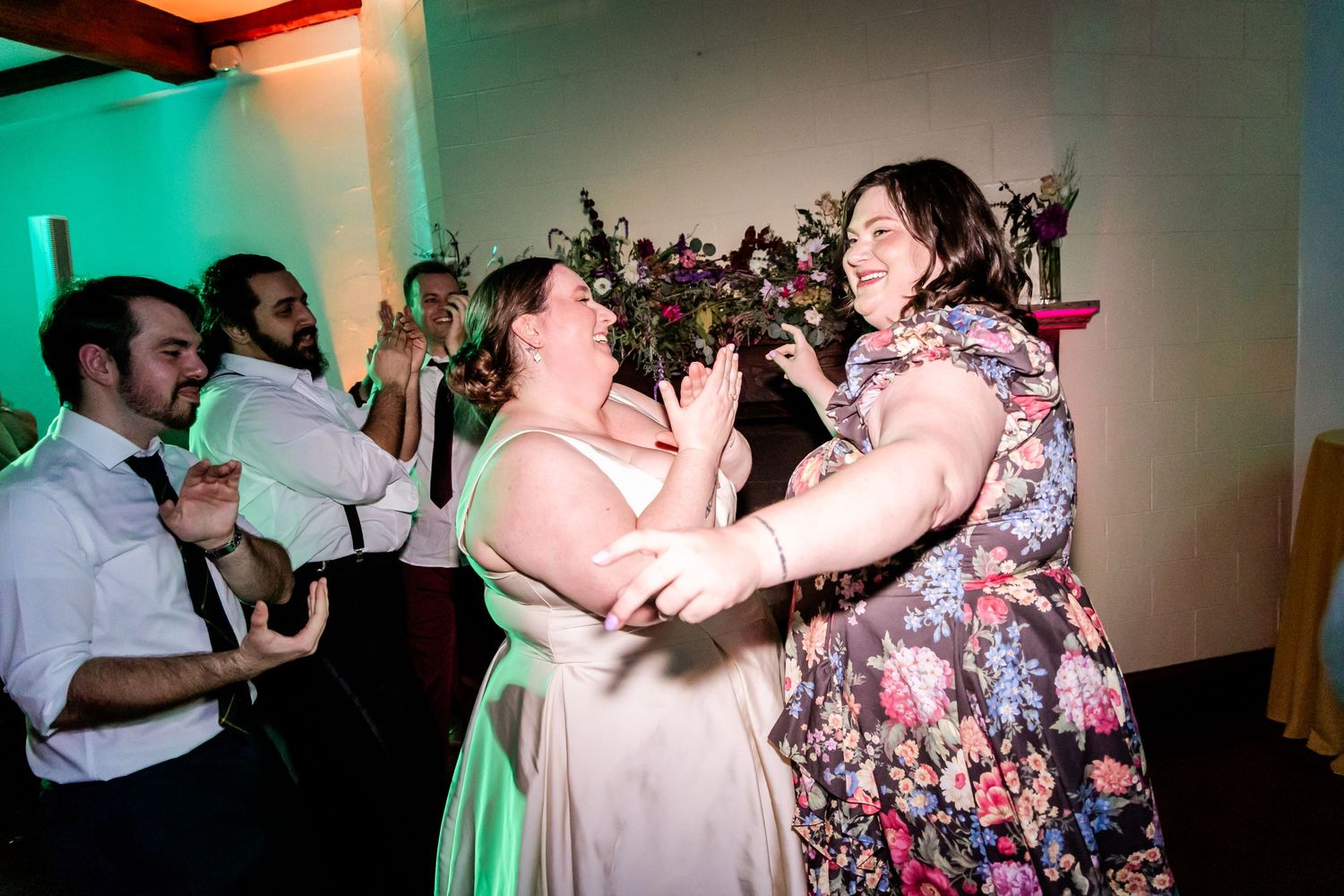 Energetic wedding reception dance party with colorful lighting.
