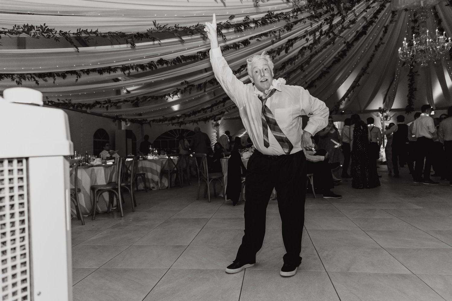 Black and white photo of wedding guests dancing at reception.