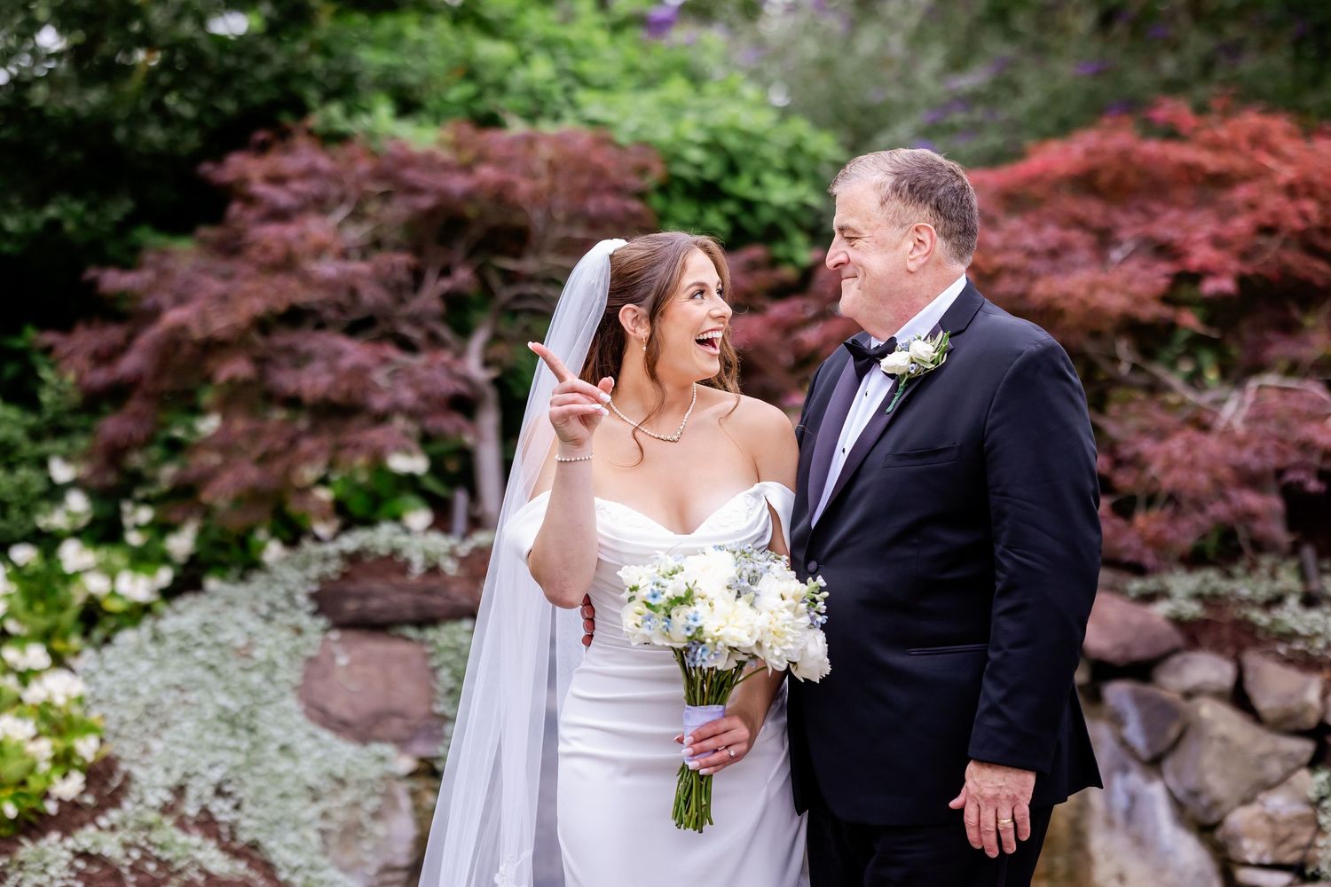 Outdoor wedding portrait with beautiful garden scenery featuring red maple trees and natural stone.