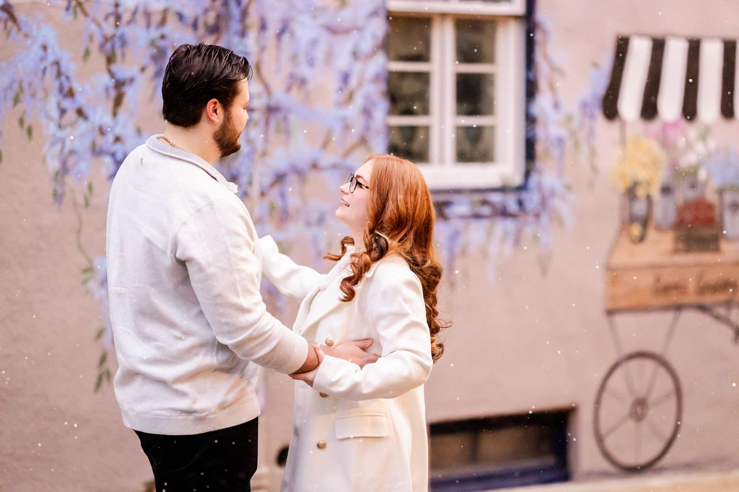 A couple dancing together in a romantic pose against a soft blurred urban background with a bicycle visible.