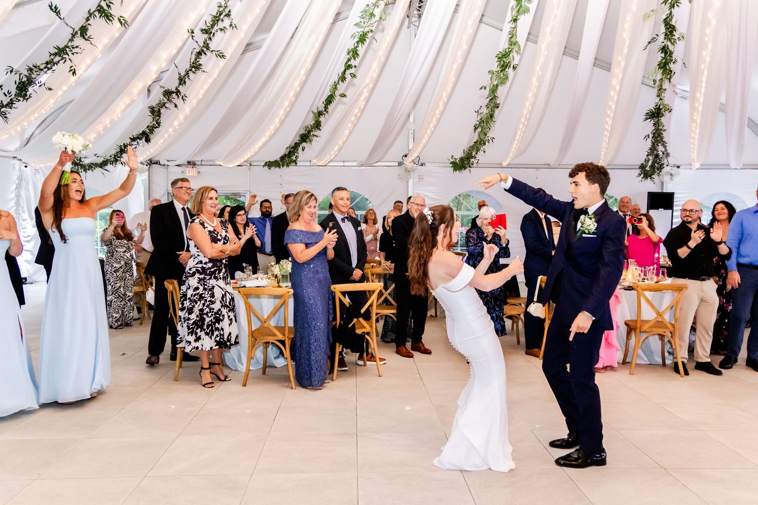 Wide view of wedding ceremony setup under white tent with guests seated.