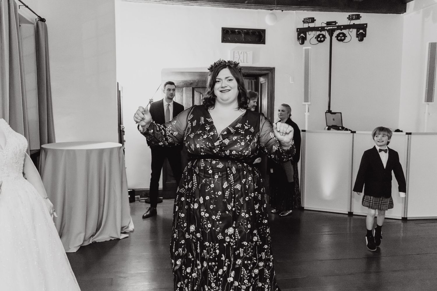 Dancing guest in floral dress celebrates on reception dance floor in black and white photo.